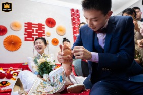 The groom cleans firework debris from the bride’s foot at their home in Taiyuan, Shanxi, China, as she laughs nearby